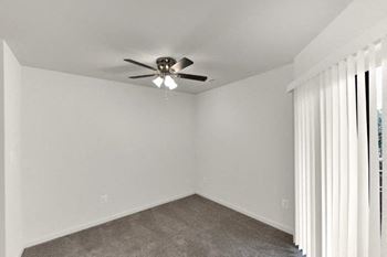 an empty living room with a ceiling fan